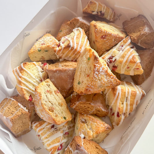 White box with assorted triangle shaped scones, including fruitcake, cranberry-orange and gingerbread.