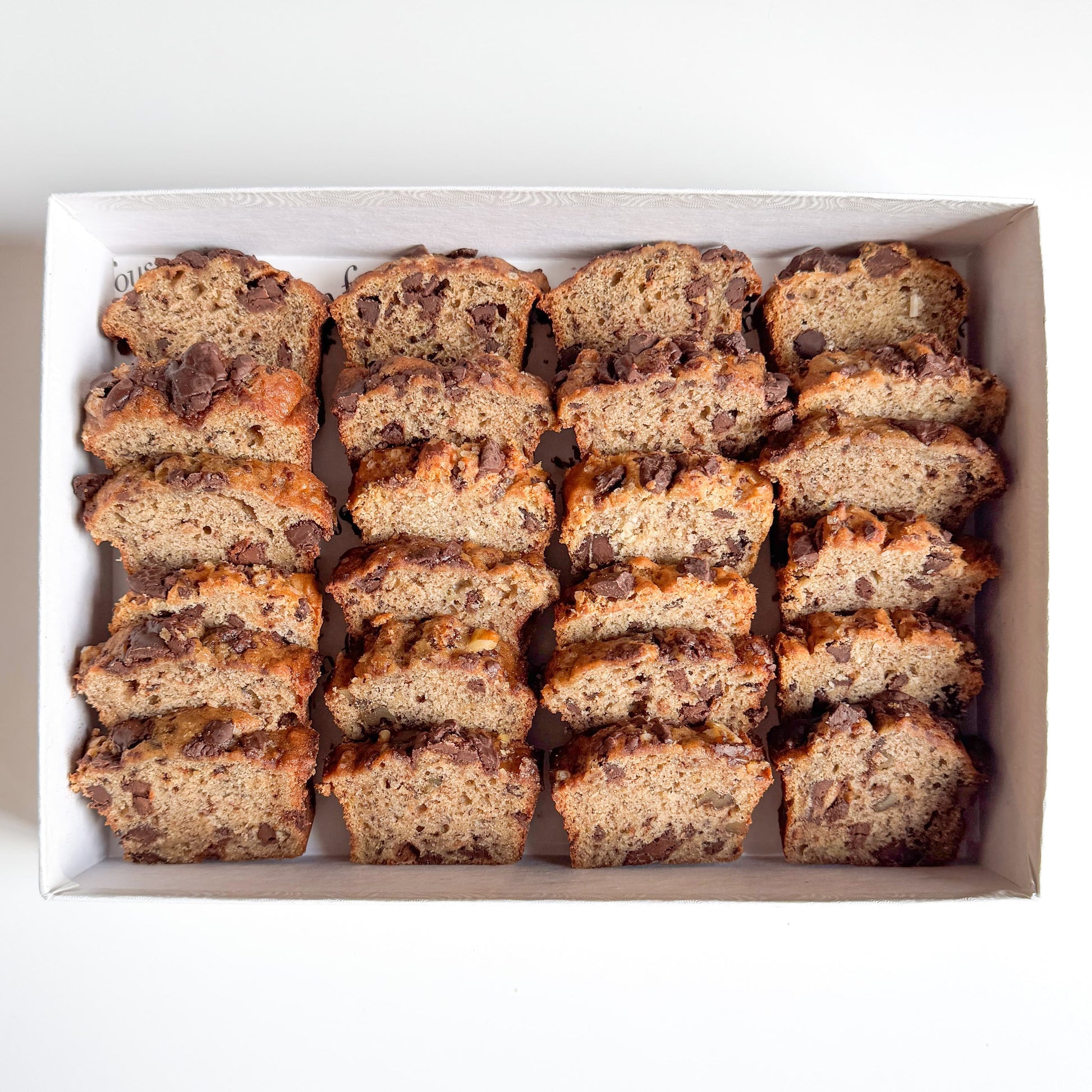 Sliced mini banana bread with chocolate chips arranged in a white box.