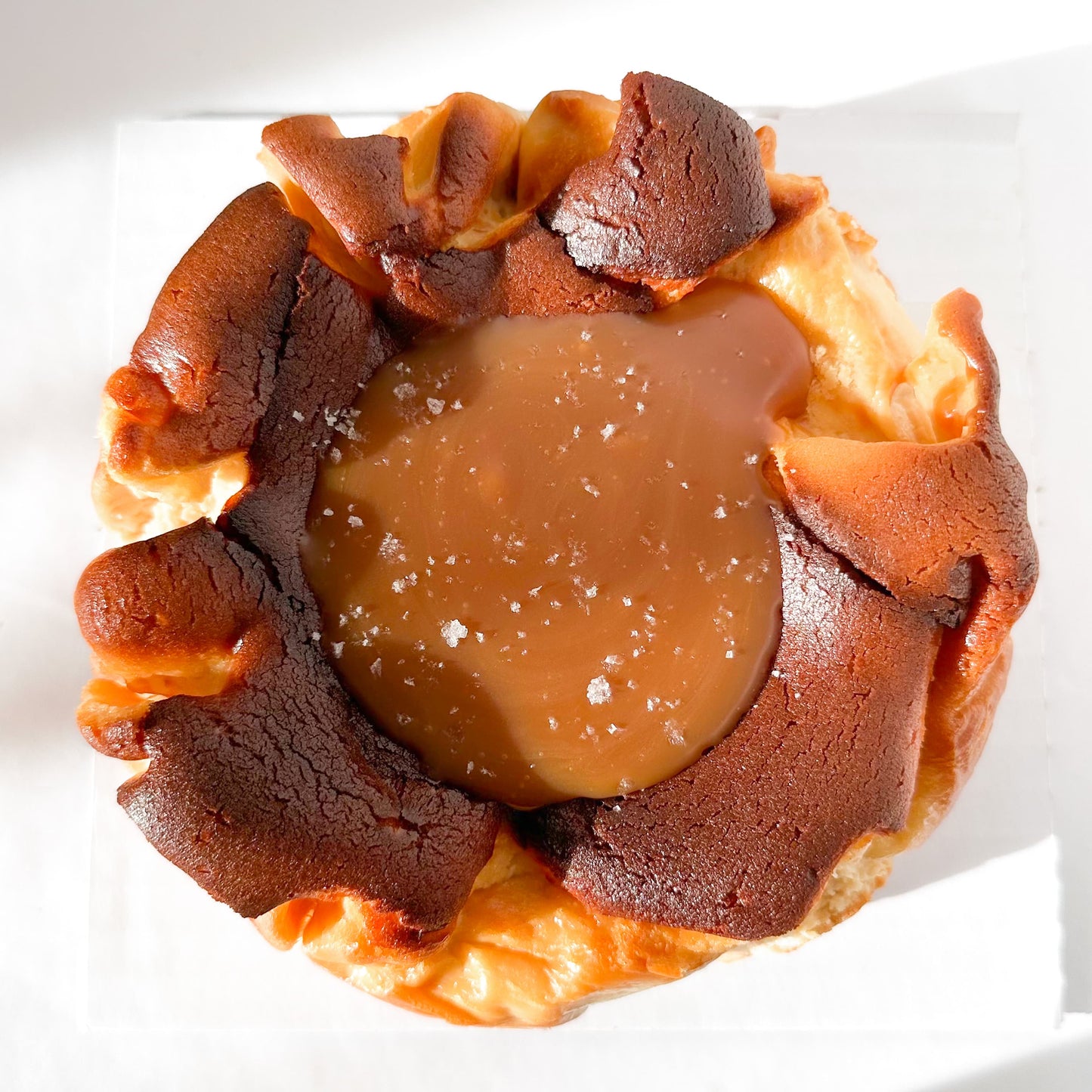Burnt basque cheesecake topped with a pool of caramel and sprinkled with flakey sea salt.