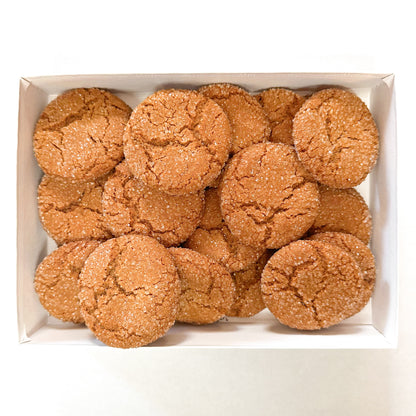 Box filled with chewy gingerbread cookies rolled in sugar on a white background.