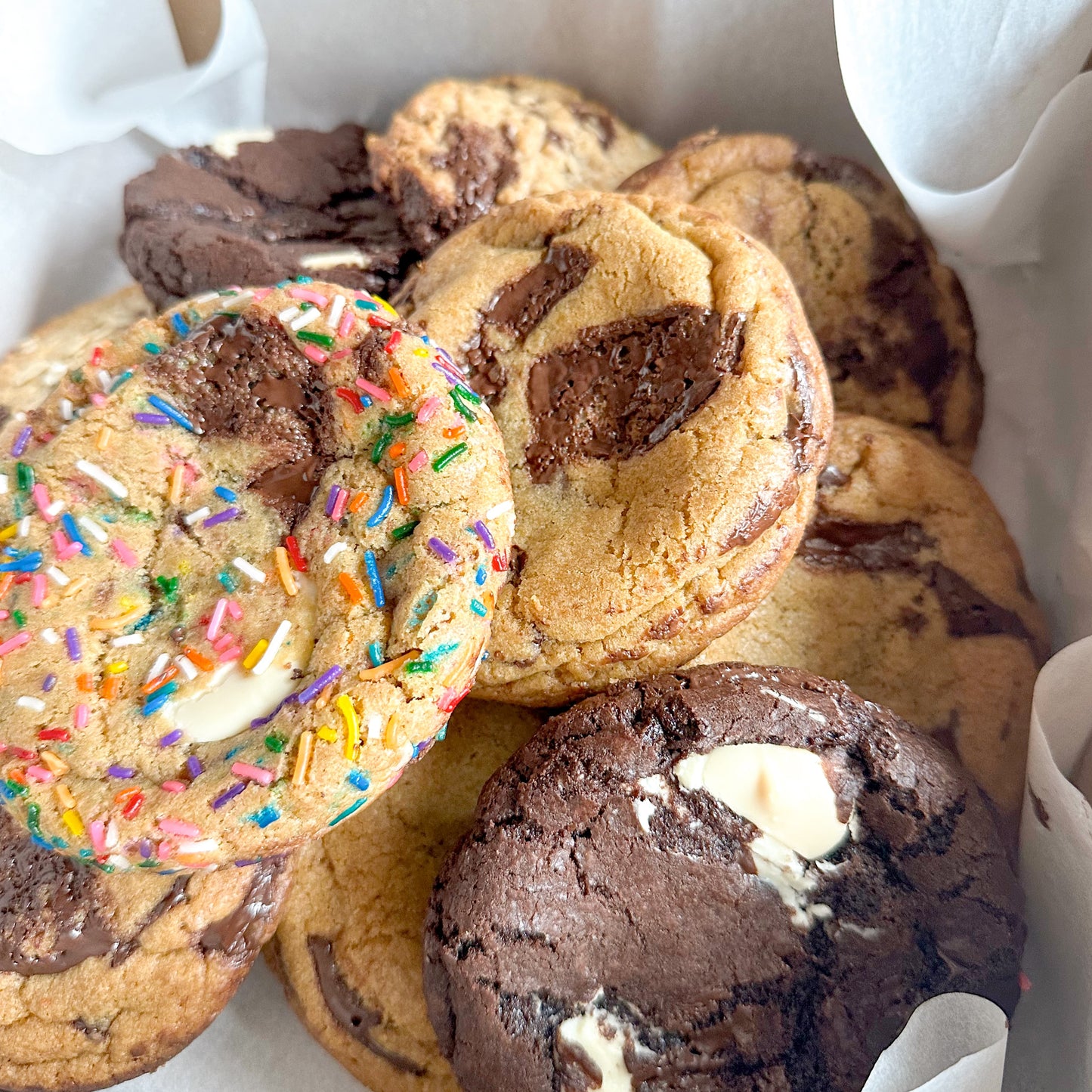 Assorted cookies including chocolate chip, marble, sprinkle confetti, and double chocolate cookies in a box.