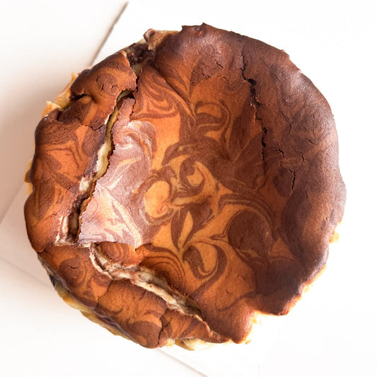 Baked marble basque cheesecake, caramelized burnt edges on a white background.