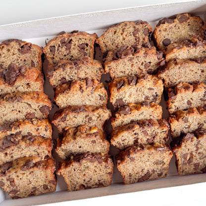 Sliced mini banana bread with chocolate chips arranged in a white box.