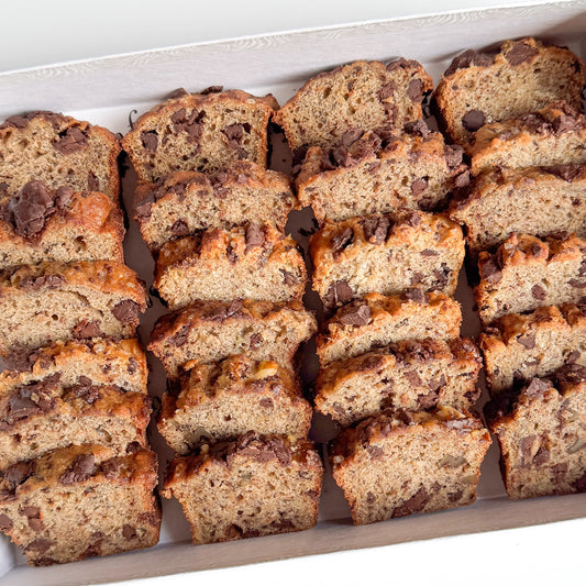 Sliced mini banana bread with chocolate chips arranged in a white box.