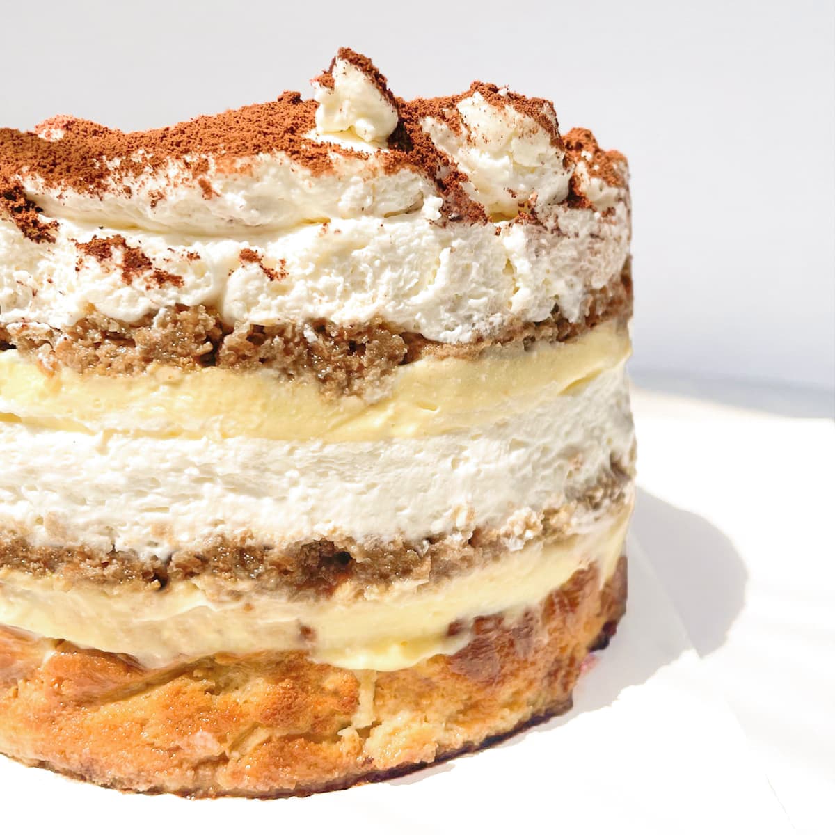 Burnt basque cheesecake topped with a tiramisu including layers of whipped cream, vanilla chantilly cream, espresso soaked lady fingers and cocoa powder