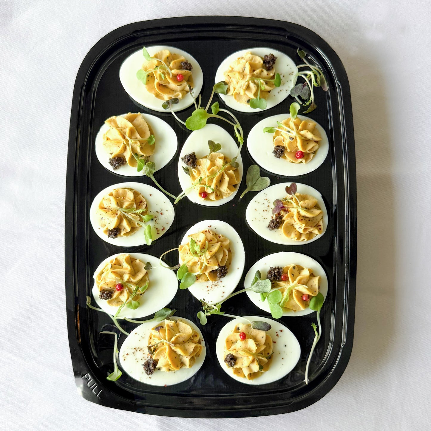 Ready to serve platter filled with truffle deviled eggs garnished with herbs.
