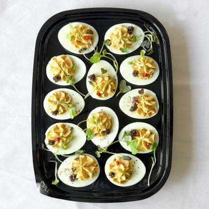 Ready to serve platter filled with truffle deviled eggs garnished with herbs.