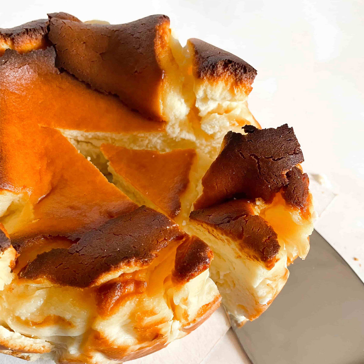 A slice of burnt basque cheesecake being served on a white table.