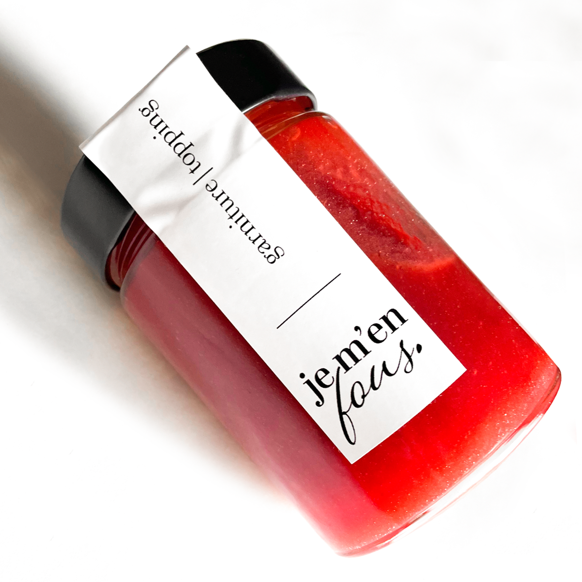 A strawberry topping jar for cheesecake on white table.