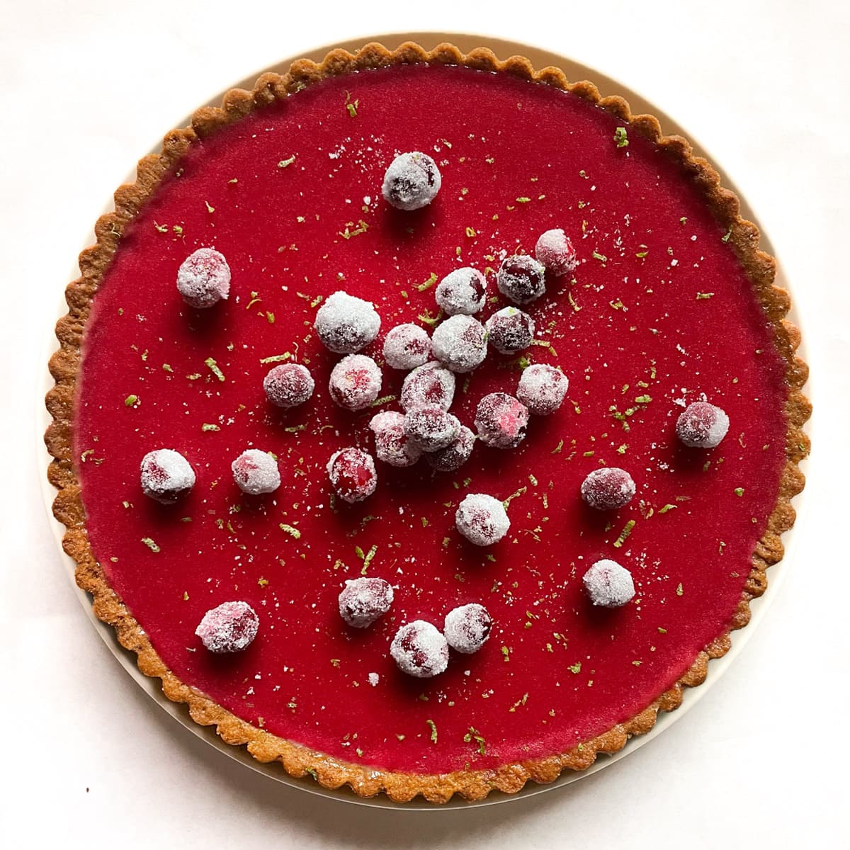 cranberry lime tart with graham cracker crust and topped with sugared cranberries